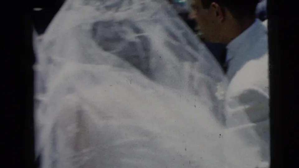Soft 8mm close-up from the Moline wedding, centered on the bride's veil and white dress fabric with a nearby guest partly seen.
