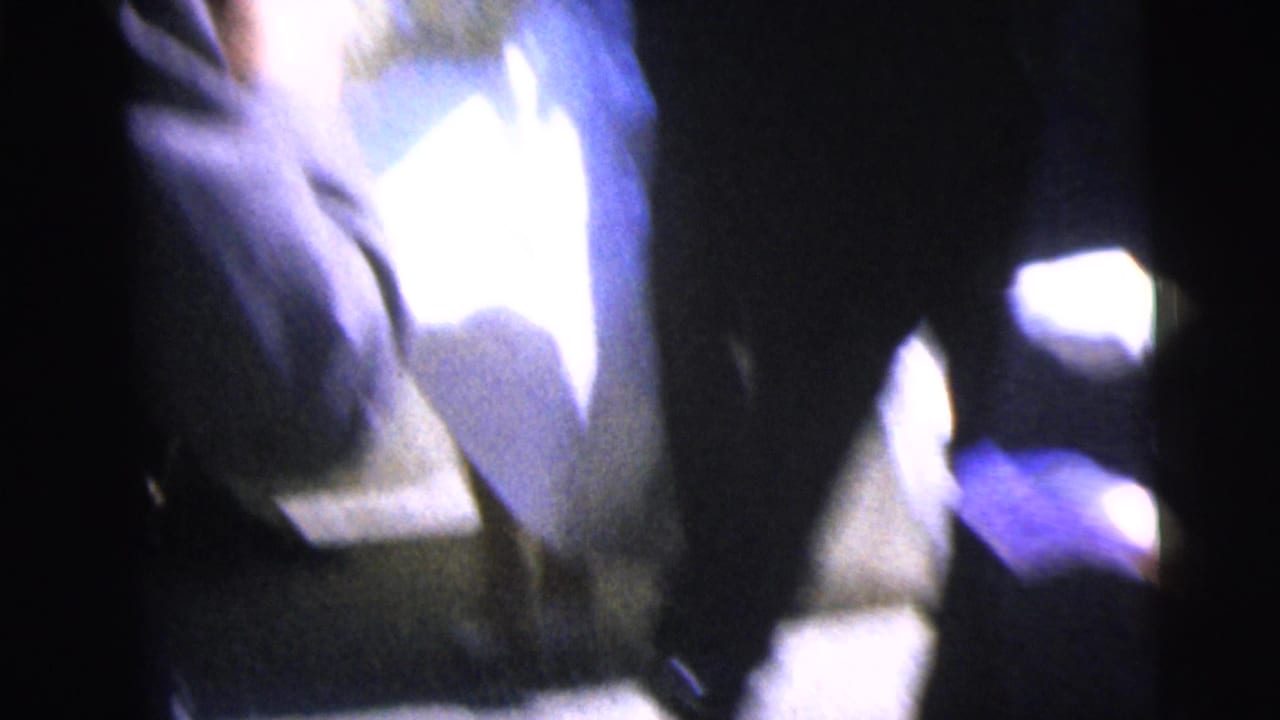 Blurred close handheld view of people in formal clothing near the camera.
