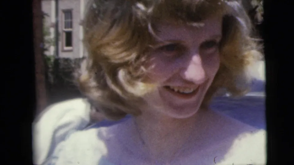 Close 1962 Moline wedding frame of the bride smiling outdoors, with soft focus and surrounding guests partly visible.