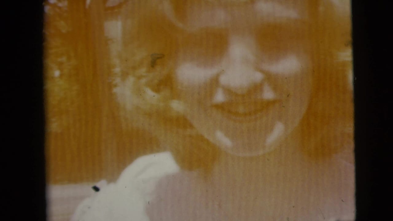 Faded orange-tinted frame of the same smiling young woman on damaged film.