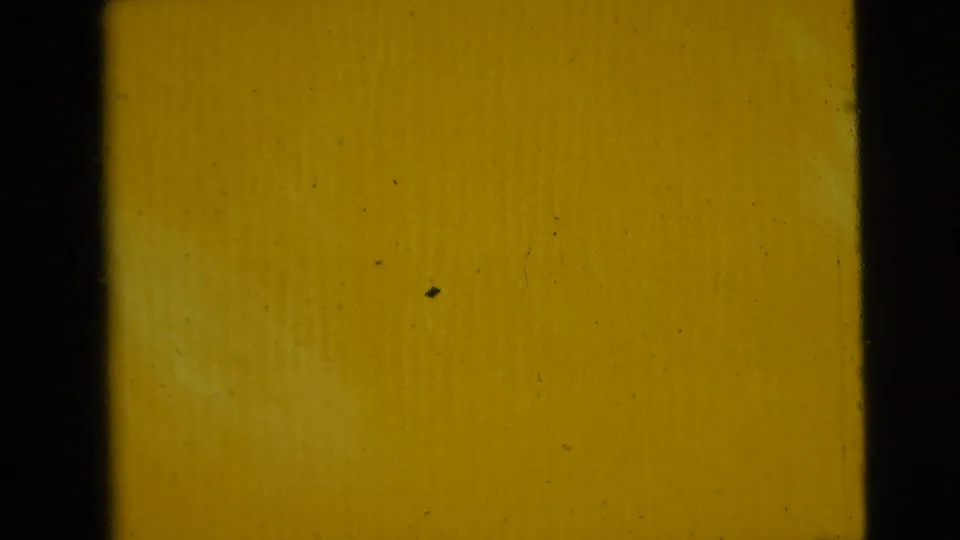 A yellow-orange 8mm frame shows heavy fading, dust, and grain, with the subject no longer clearly visible.