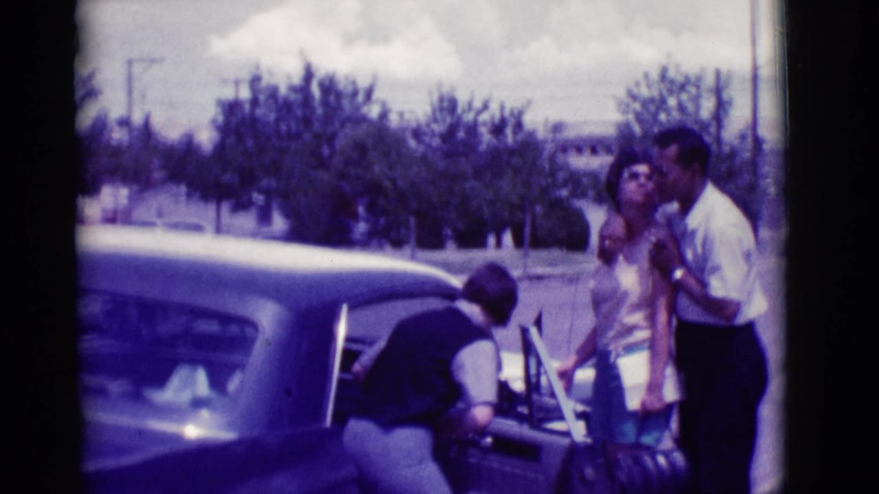 A woman leans into the back seat of a classic sedan while a man and another woman stand close by in the Clarkdale street scene.