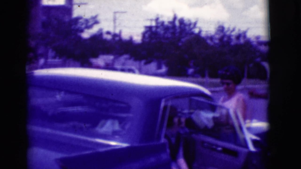 Woman beside an open classic car door in Clarkdale, Arizona, with a person partly visible inside the vehicle.