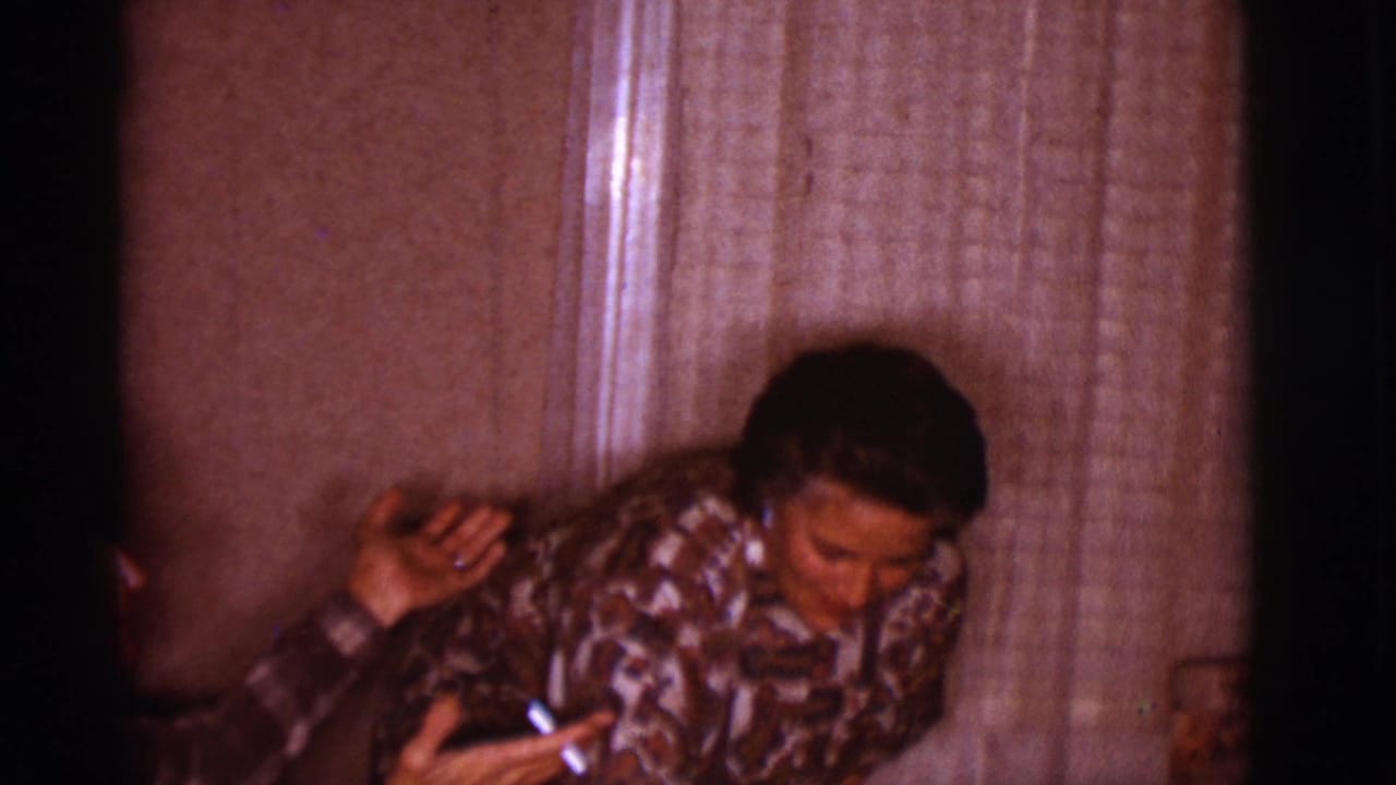 Woman leaning forward beside a man in a warm living room.