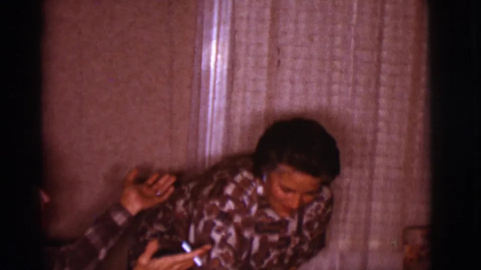 In a 1966 Clarkdale, Arizona home-movie frame, a woman in a patterned shirt leans forward while a man sits close beside her.