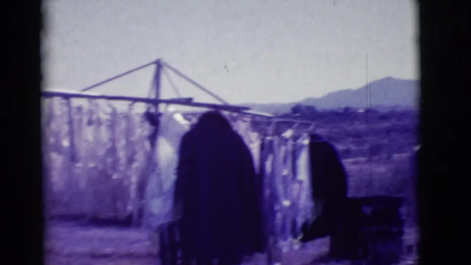 Laundry hangs from a clothesline in the arid Clarkdale, Arizona landscape, with scrubland and mountains visible beyond the home-movie frame.
