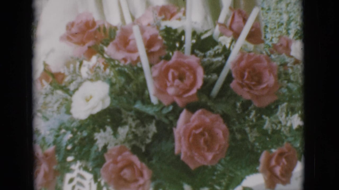 Close view of pink roses, white flowers, greenery, and white candles in a porch bouquet.