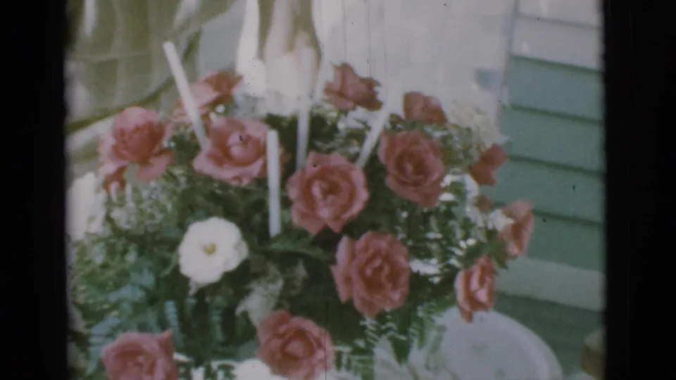 1966 Clarkdale, Arizona 8mm frame showing the rose and candle arrangement sitting on a small white porch table.