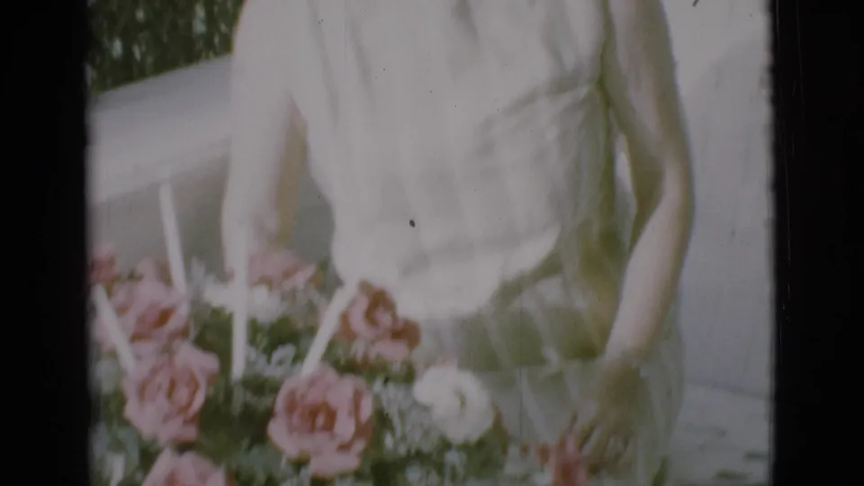 1966 Clarkdale frame showing a partial figure in a white dress behind the pink and white rose arrangement.