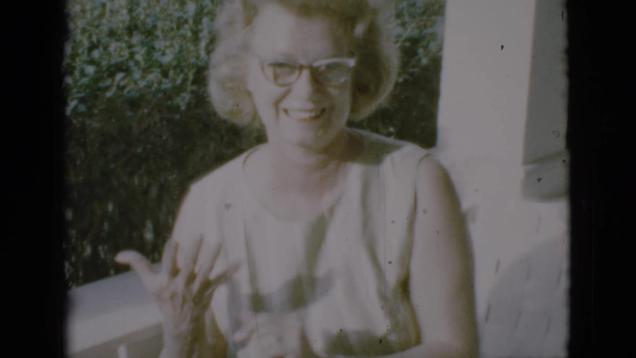The woman remains on the porch in the Clarkdale 1966 clip, smiling near a white post with greenery behind her.