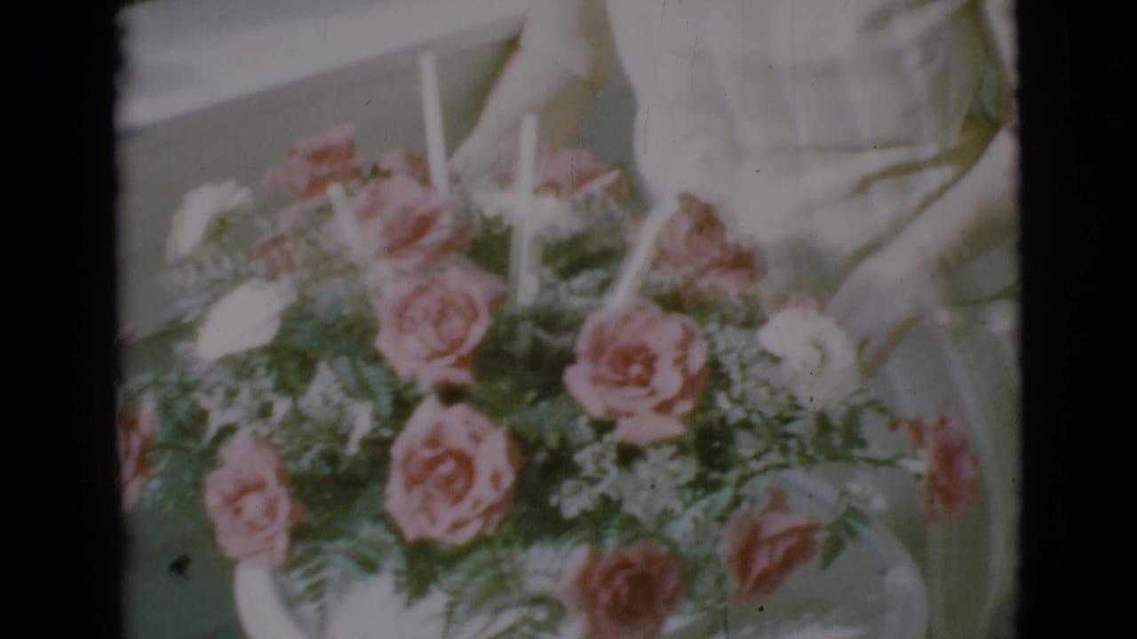 Close view of pink and white roses with greenery as hands arrange the bouquet.