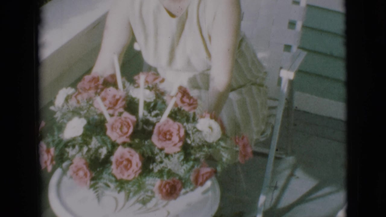 Woman seated behind a round table with a pink and white rose bouquet.