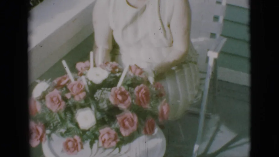 The seated woman remains partly visible behind a large rose arrangement on a sunny Clarkdale porch in 1966.