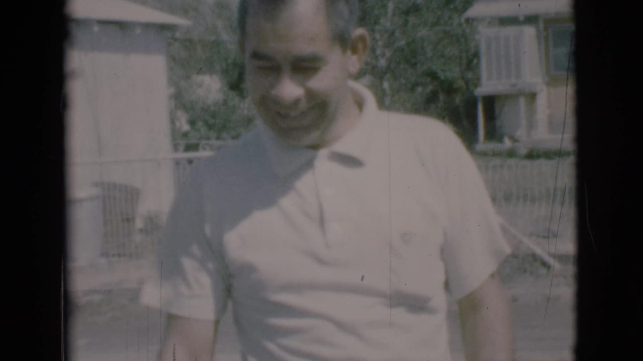 Man in a light polo smiles close to the camera outdoors.