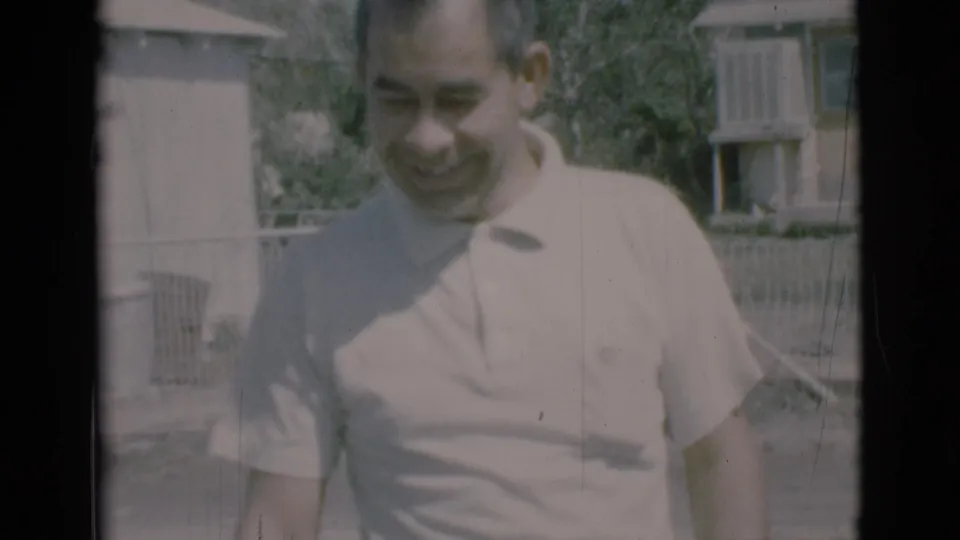 A smiling man in a light polo stands closer to the camera in the Clarkdale, Arizona home-movie scene.