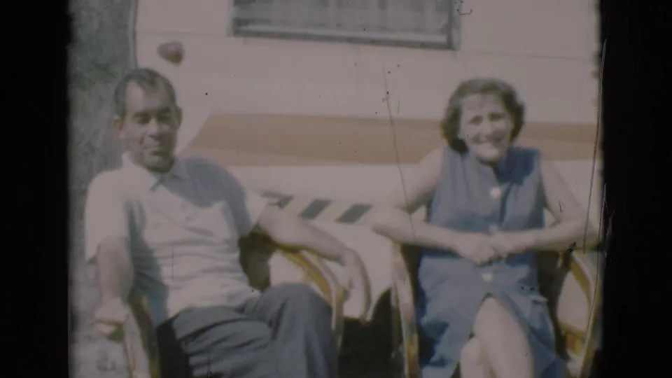 The couple smiles toward the camera while seated in lawn chairs outside the camper in Clarkdale, Arizona.