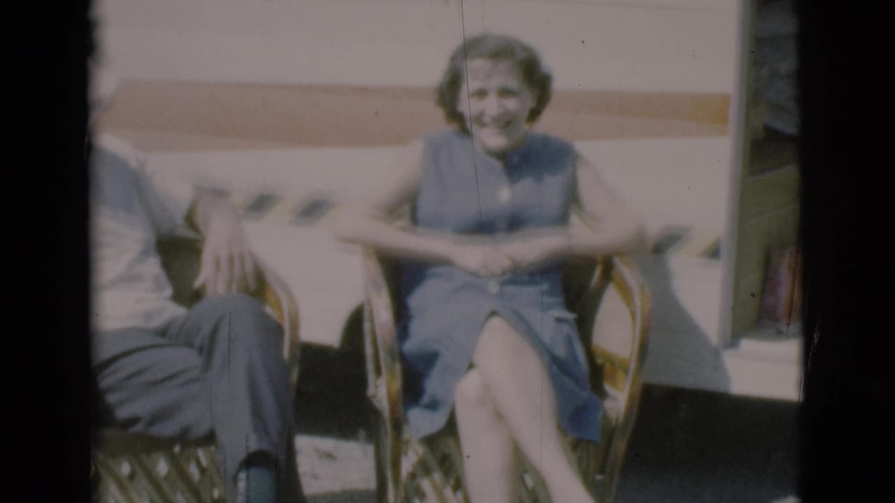 Woman seated in a wicker chair with part of the man visible beside her.
