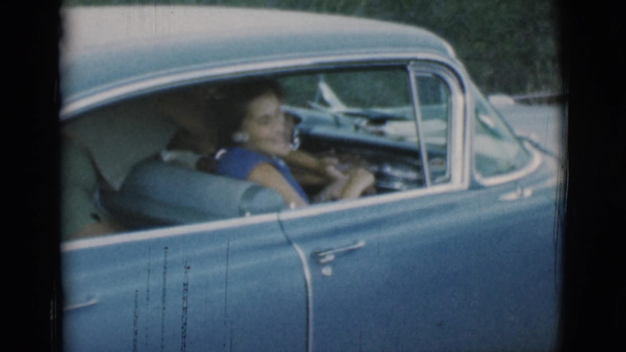 Woman seated in the blue car with the driver-side door closed.