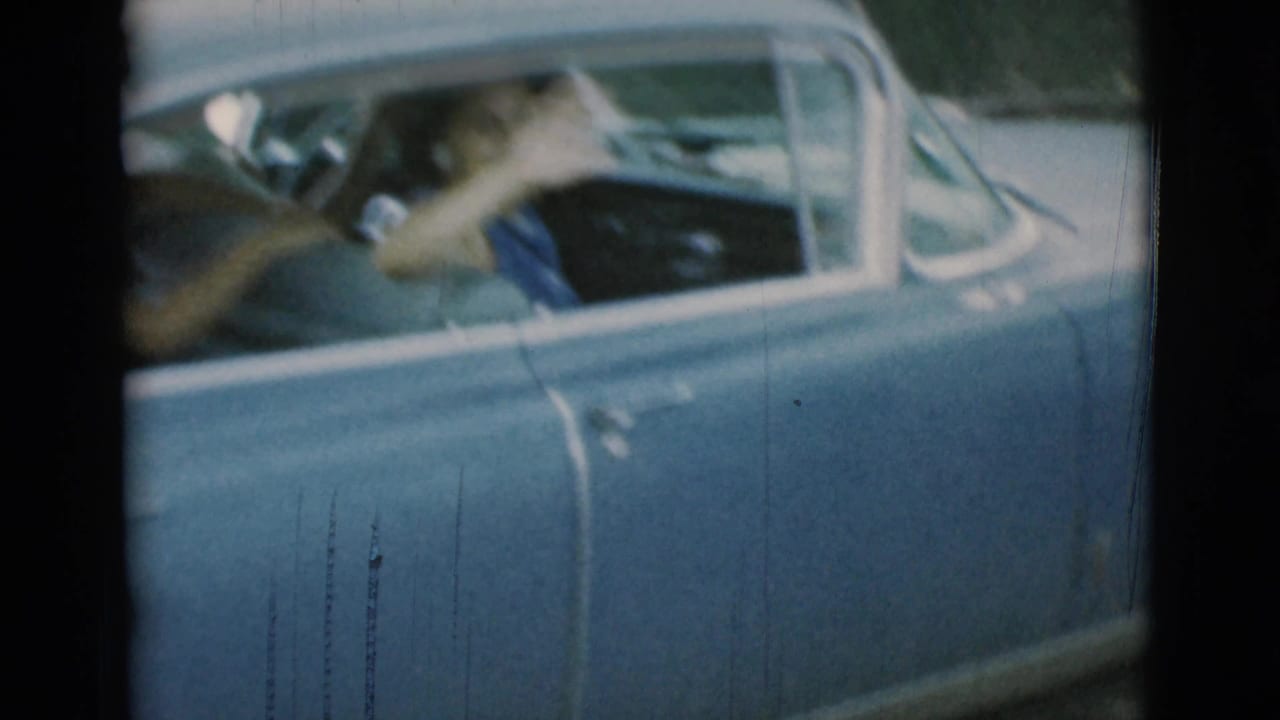 A woman appears at the wheel of a light blue classic car in 1966 Clarkdale, Arizona home-movie footage, seen close through the open side window.