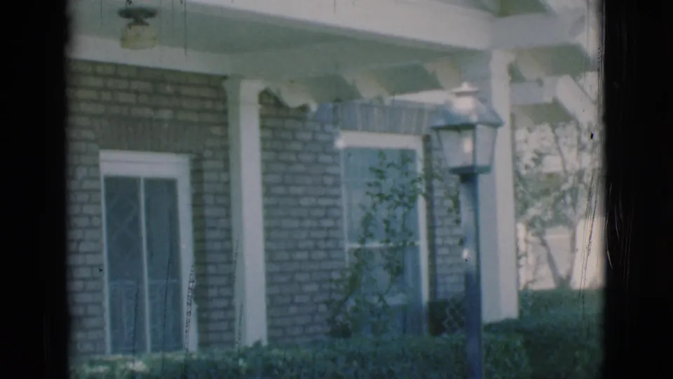 1966 Clarkdale, Arizona frame of a brick residential exterior with porch columns, hedges, window screens, and a lamppost in the yard.