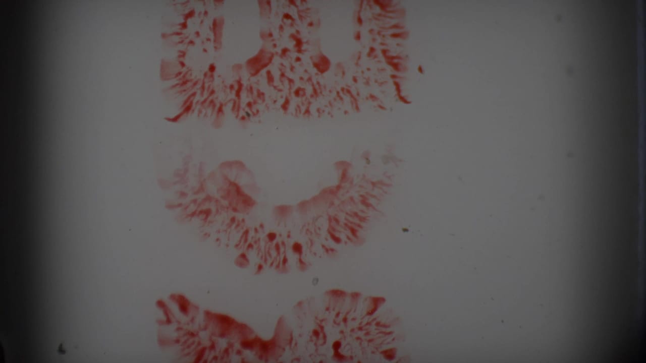 Blank 8mm roll section showing red circular frame-like markings, faded exposure, dust, and dark side vignetting.