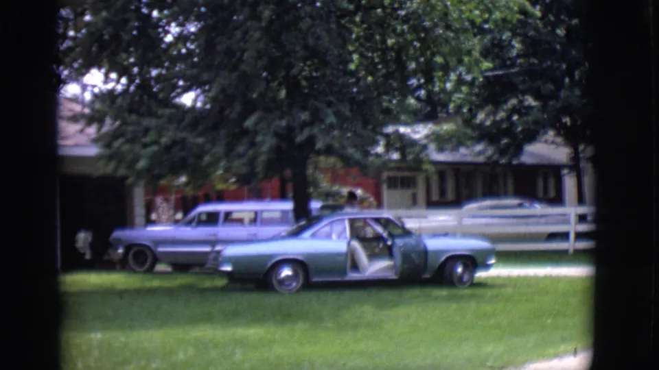 The final frame shows the open-door classic car on the lawn with a station wagon and suburban house in the background.