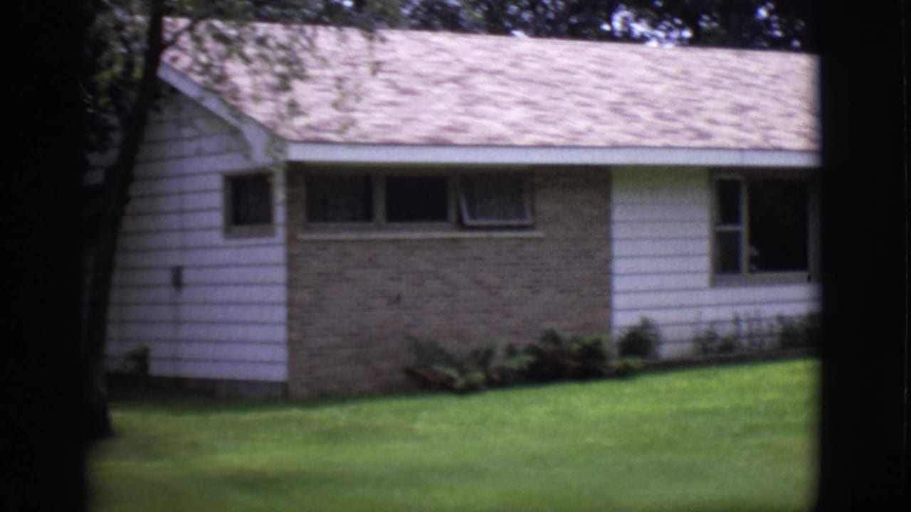 Ranch-style house with brick and white siding behind a green lawn and trees.