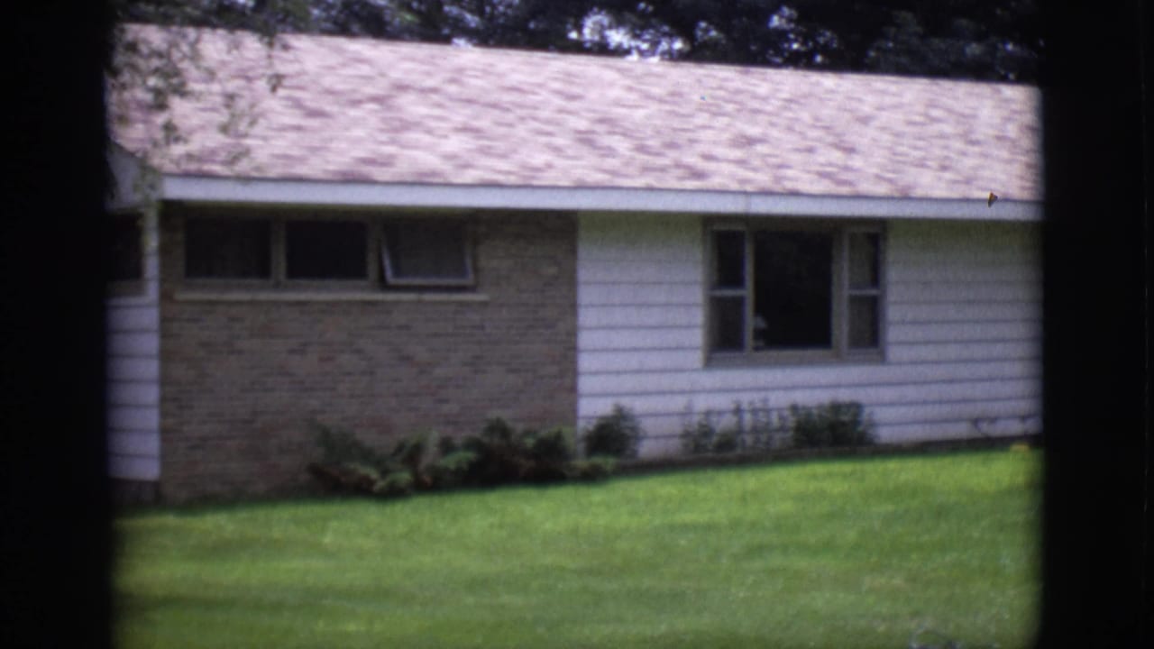 Single-story house with white siding, brick wall section, front windows, and green lawn.