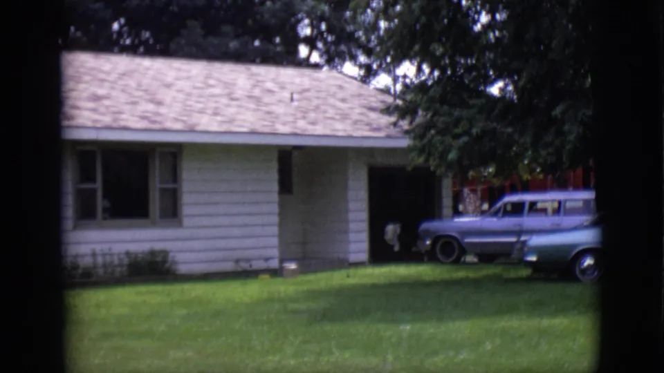Clarkdale, Arizona 1966 frame showing the ranch-style house, front lawn, shaded driveway, and two parked station wagons.