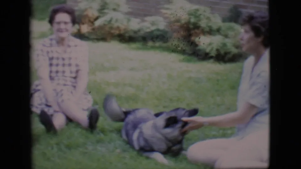 Two women sit on the grass in Clarkdale, Arizona, while a dark dog lies nearby in this 1966 home-movie frame.