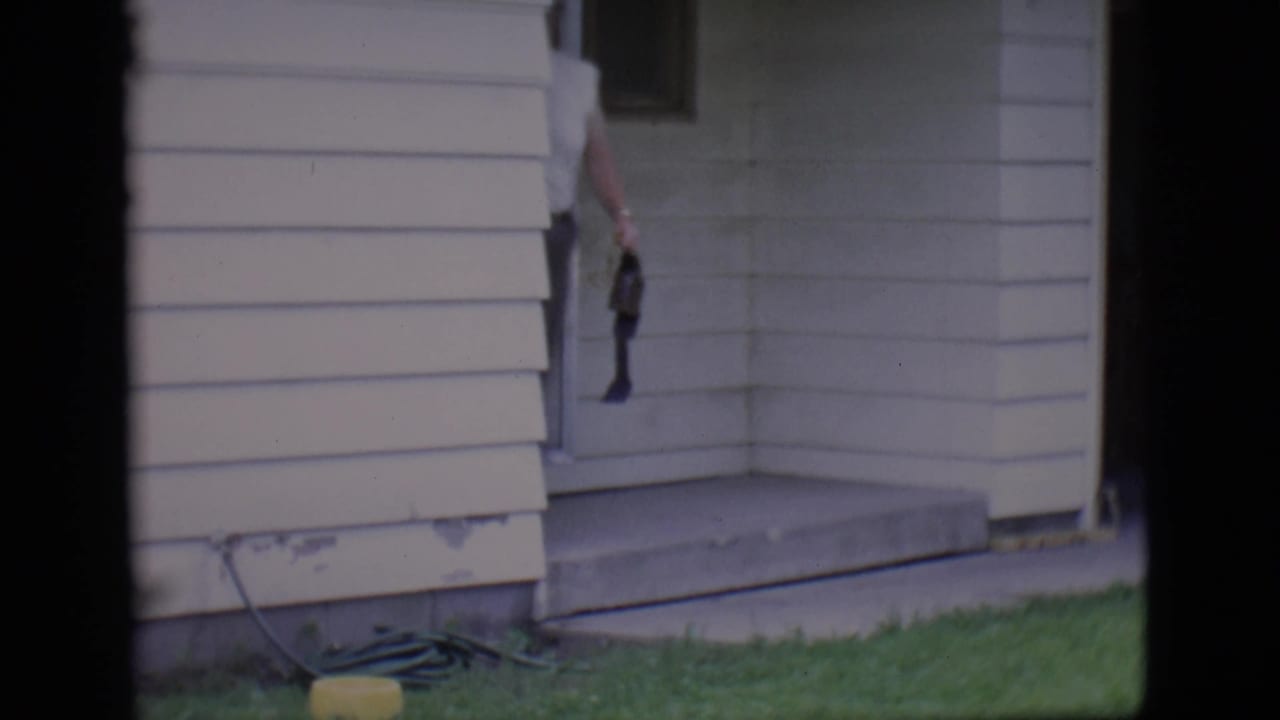 House doorway and concrete steps with a man partly visible holding a belt.