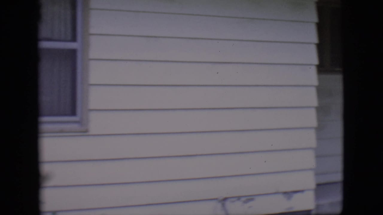White-sided house exterior with window and dark film border.