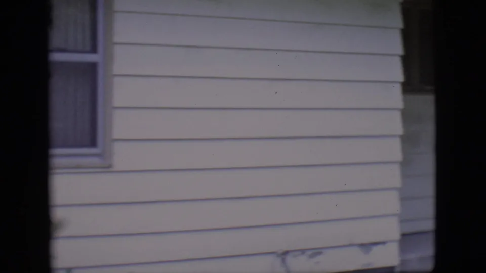 Opening frame of a white-sided house exterior in the supplied 1966 Clarkdale, Arizona home movie, partly obscured by dark film border.
