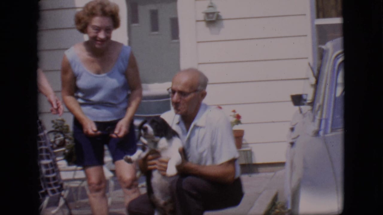 The 1966 Clarkdale backyard scene shows a smiling woman and an older man crouched with a black and white dog beside house siding and a car edge.