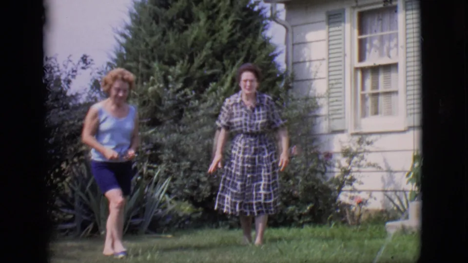 The final 1966 Clarkdale frame shows two women in a backyard near shrubs and a shuttered window on a pale house.