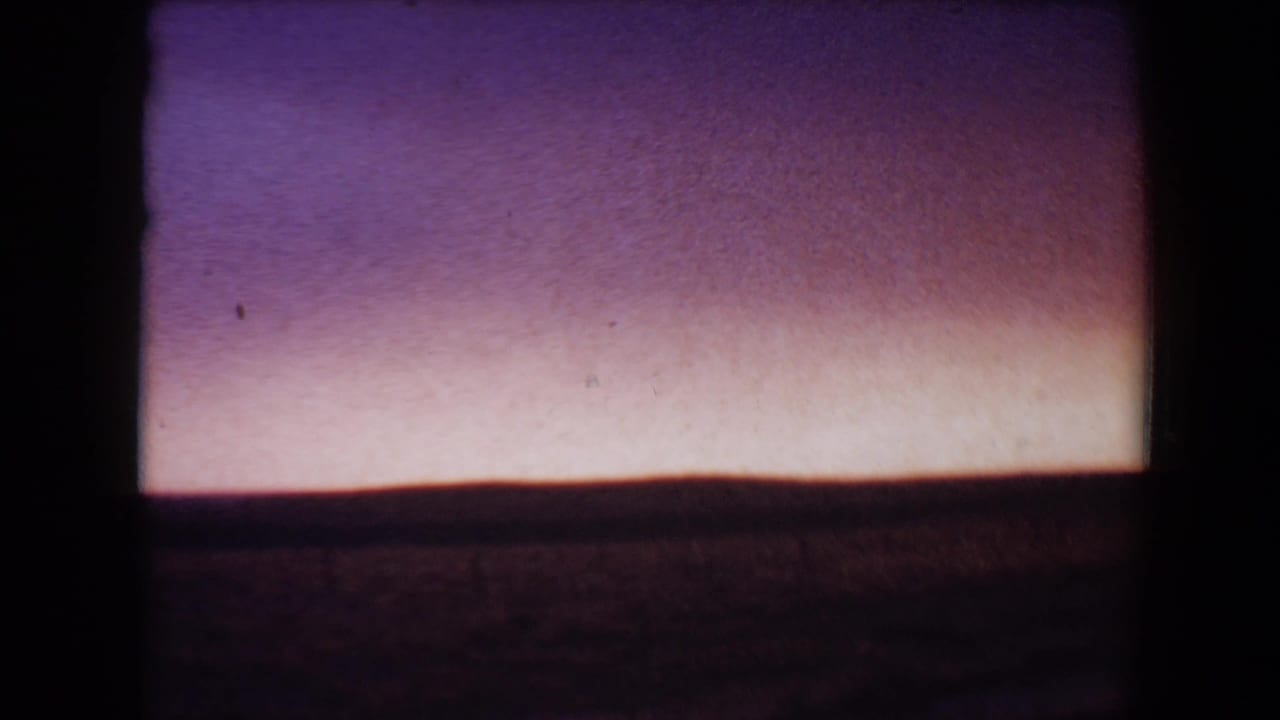 Purple dusk sky above a dark low horizon with visible 8mm frame edges.