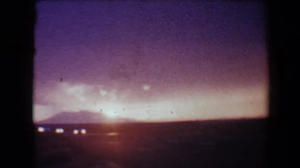 Late clip frame from 1967 Flagstaff 8mm footage, showing the horizon glowing behind low hills under a purple sky.