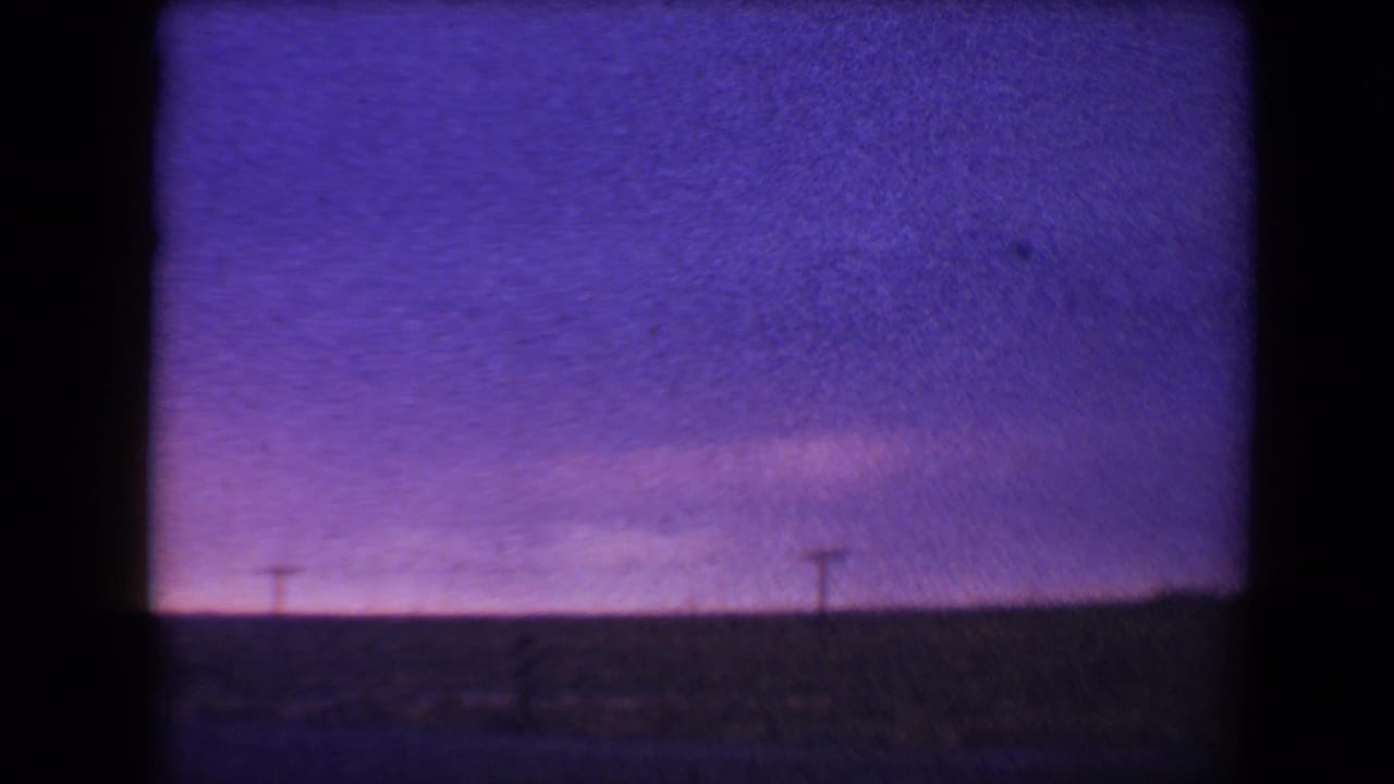Purple twilight sky over a dark low horizon with distant utility poles.