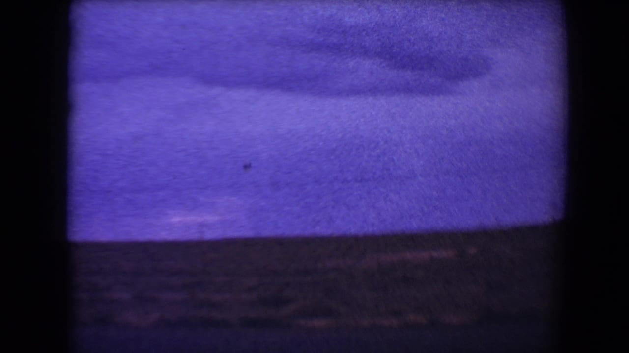 Soft purple-tinted roadside landscape with low hills and dark 8mm frame borders.