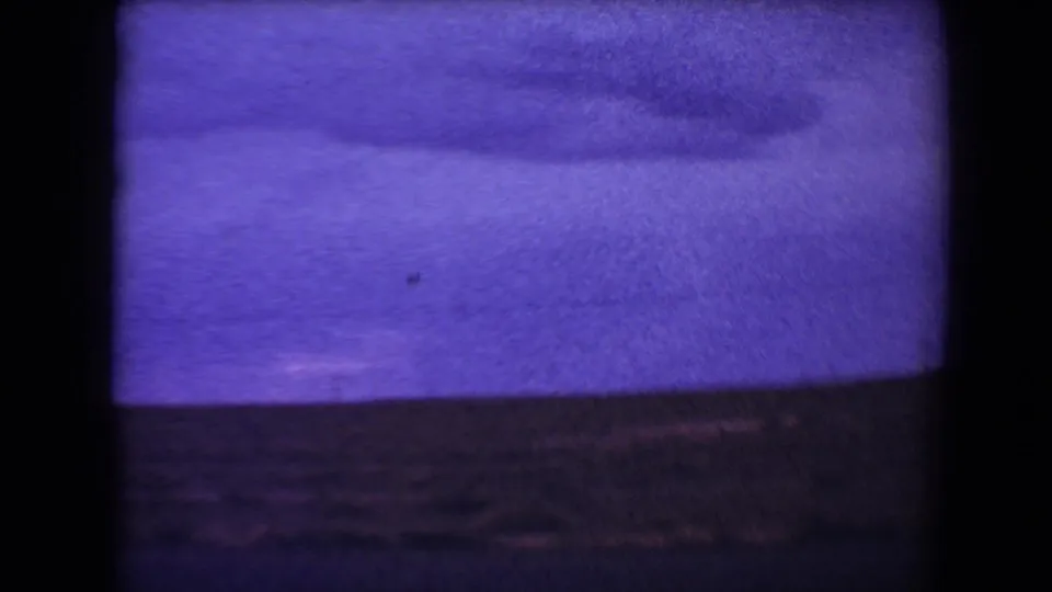 1967 8mm footage from Flagstaff, Arizona, showing a soft roadside landscape under a purple sky before the camper is fully visible.