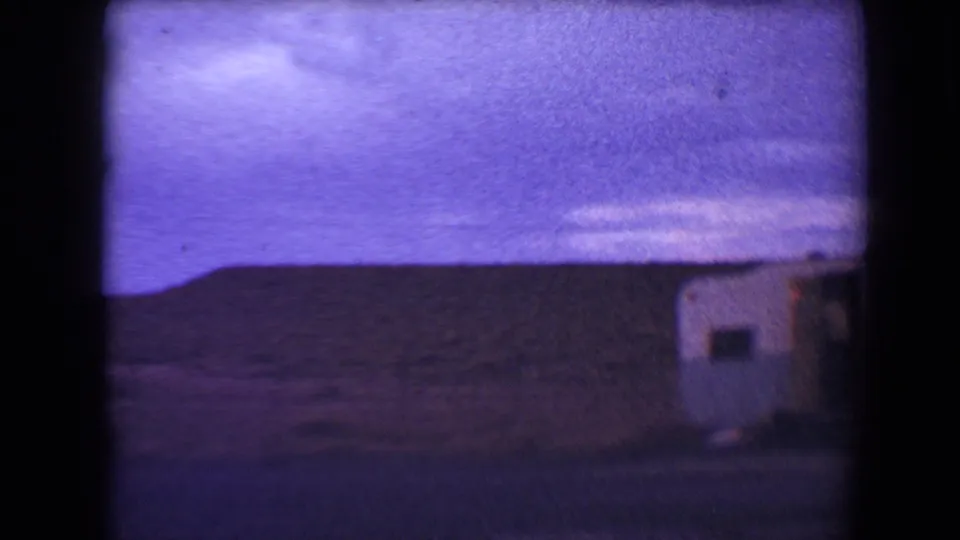 A small blue and white camper appears at the right edge of a 1967 Flagstaff roadside view under a purple-tinted sky.