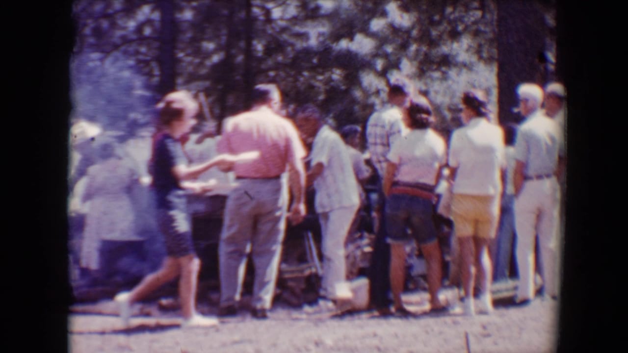 Adults in summer clothing and hats gather near barbecue tables at a 1967 Flagstaff outdoor event.