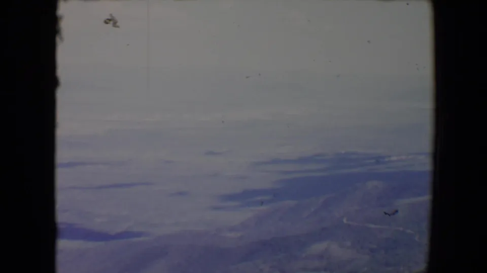Aerial-looking 1967 Flagstaff-area frame with a mountain slope at right, pale lake shapes, and muted blue-gray film color.