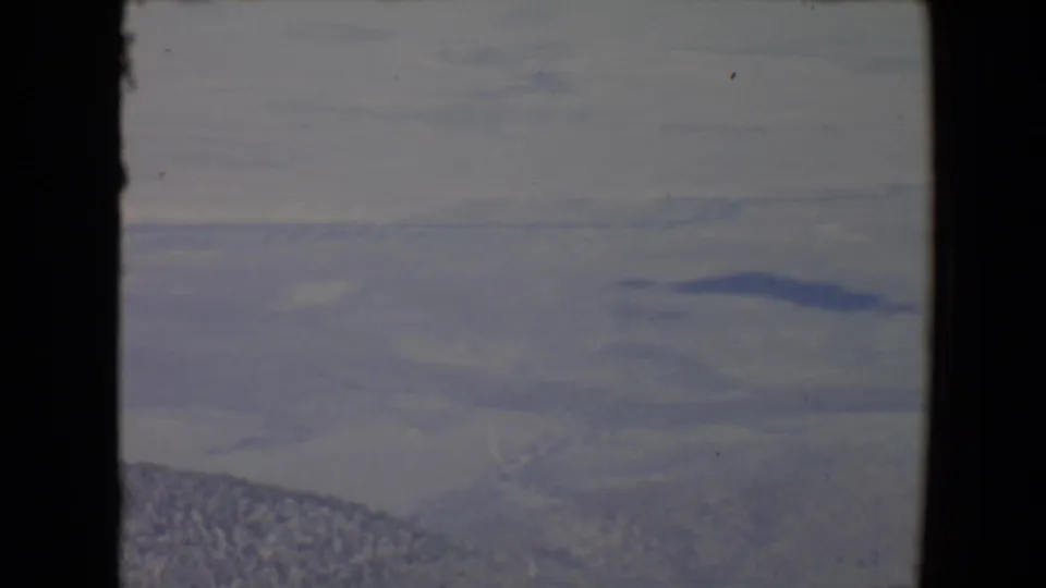 1967 Flagstaff-area 8mm view of a hazy valley and distant mountain ridges framed by dark borders.