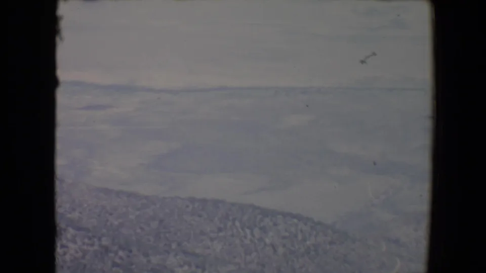 1967 Flagstaff-area landscape frame showing distant ridges, valley haze, and dark film or window edges.