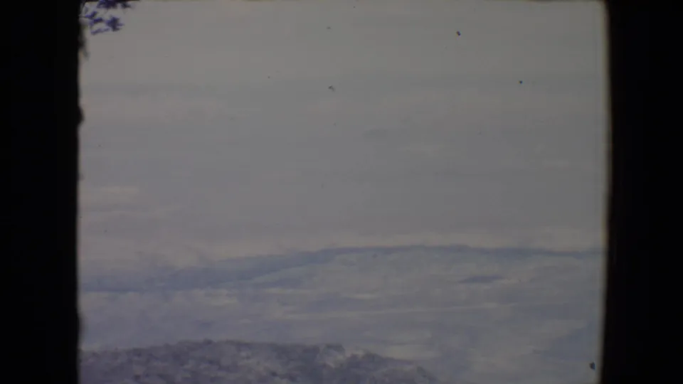 1967 Flagstaff-area 8mm landscape view with distant hills, valley haze, and visible frame border.