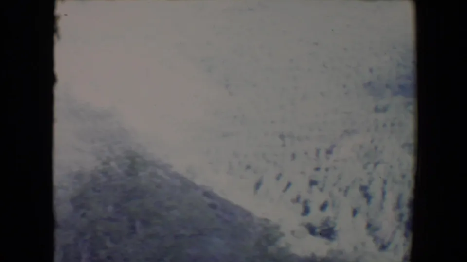 Soft 1967 home-movie view near Flagstaff showing a bright hillside, shadowed foreground terrain, and sparse vegetation.