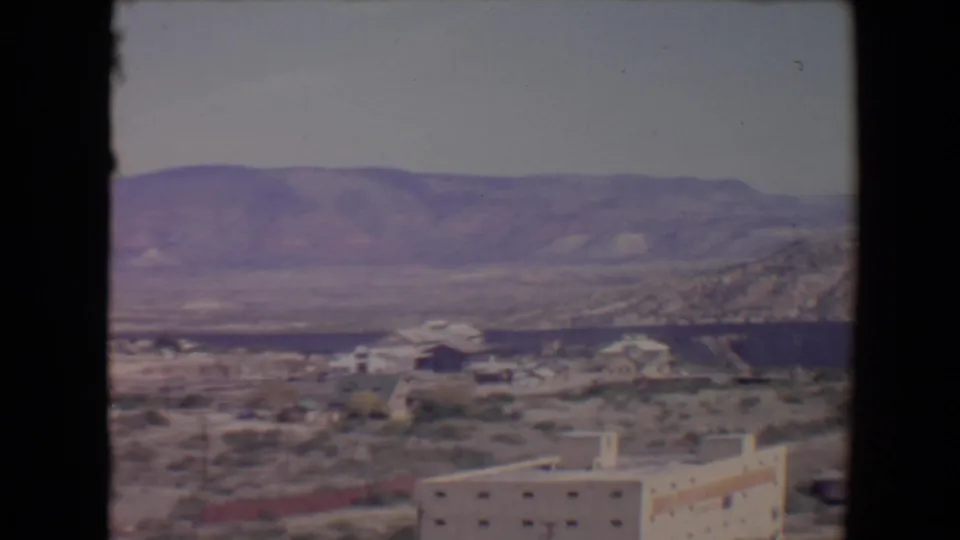 Flagstaff, Arizona 8mm frame showing valley housing, sparse vegetation, and a broad mountain ridge in muted color.