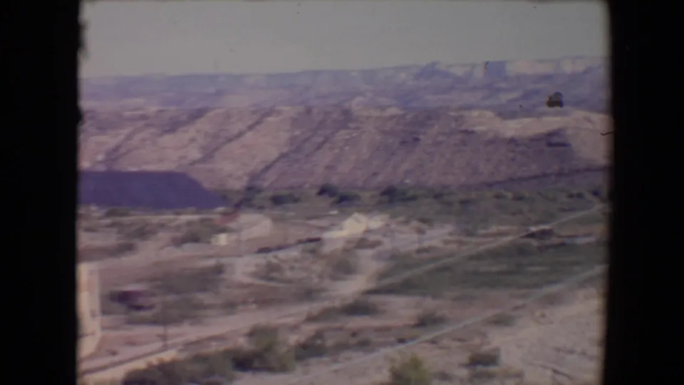 Final frame of a 1967 Flagstaff desert-valley pan, with roads, brush, scattered buildings, and rugged hills.