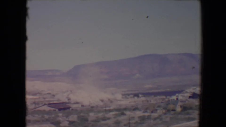 End of the 1967 Flagstaff demolition clip, with dust settling over the site and mountains visible beyond the 8mm frame edge.